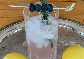 glass with flavored water and blueberries and rosemary